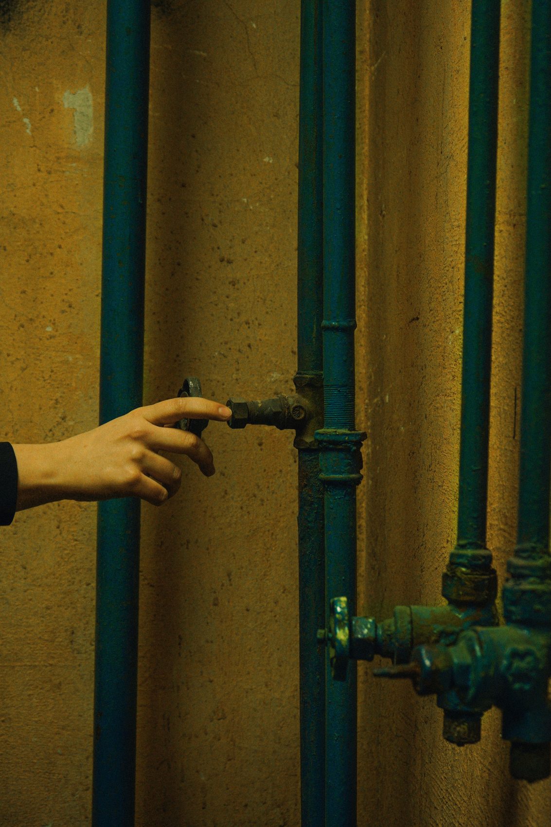 Close-up of a hand adjusting an old shut-off valve